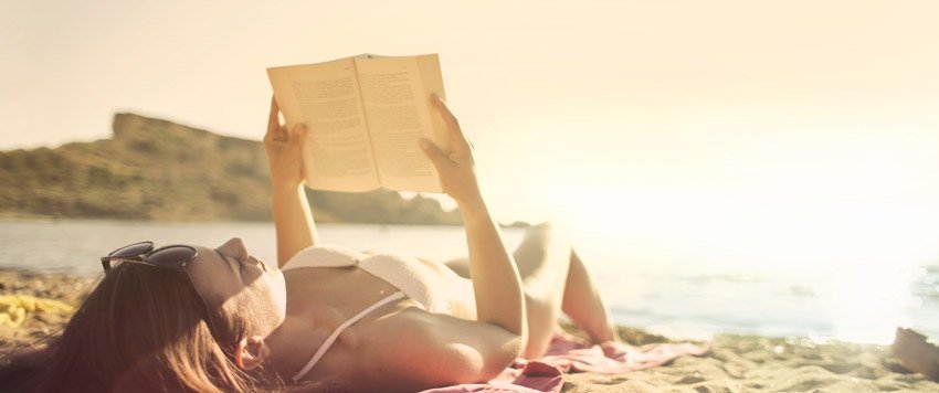 Chica leyendo libro en la playa